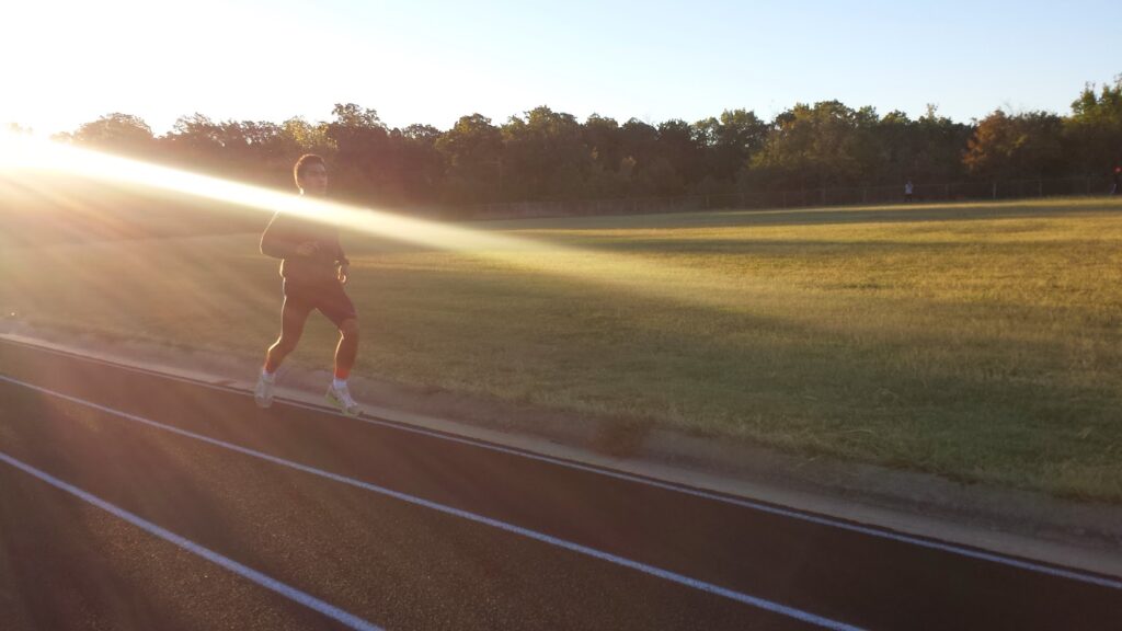 Runner on track with sunlight glare