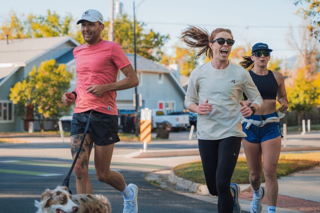 The Goal Is Not the Point 2 Three runners jogging with a dog.